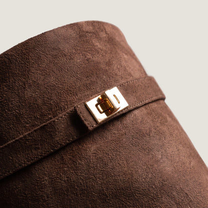 Close-up of the gold turnlock clasp on the dark brown suede shaft strap